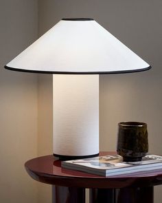 a table with a lamp on top of it next to a book and a cup