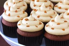 cupcakes with white frosting and orange sprinkles on a plate