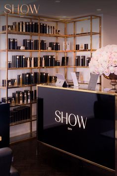 the front desk of show day with flowers in vase and bookshelves behind it