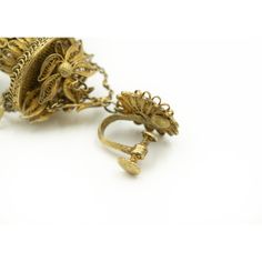 an ornate gold ring is sitting on a white surface with other jewelry items around it