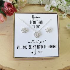 a card with two necklaces on it sitting on top of a wooden table next to flowers