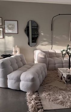 a living room filled with white furniture and pictures on the wall above it's coffee table