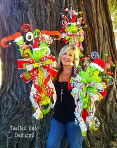 a woman standing in front of a tree with christmas decorations on her head and arms