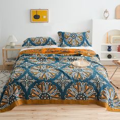 a bed with blue and orange bedspread in a bedroom next to a white wall