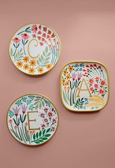 three plates with floral designs and the letters e, f, and g on them