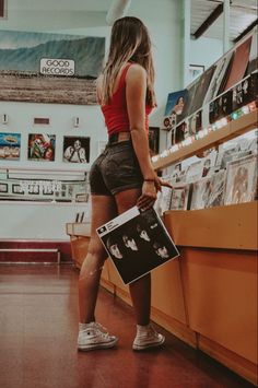 a woman standing in front of a counter holding a vinyl album and looking at it