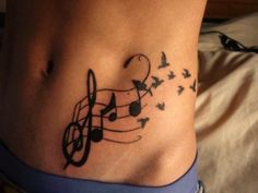 a woman's stomach with music notes and birds flying around her tattoo on the side