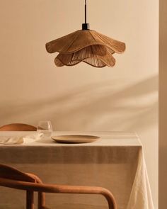 a dining room table with a plate, fork and knife under a bamboo light fixture