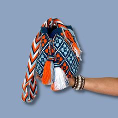 The stunning, one-of-a-kind, 100% handmade crossbody has been carefully crocheted by women from the Wayuu tribe in La Guajira, Colombia. This versatile Wayuu bag is perfect for a night out, running errands, hiking, relax on the weekend, or to take to the gym. It's convenient and light, yet still carries all the essentials. Carefully crafted using a double thread technique for the body. This piece represents approximately 1 week of work for a single artisan. Dimensions: Height: 9 inches. Width: 7 Handmade Orange Crochet Bag For Travel, Orange Handwoven Crochet Bag For Travel, Handwoven Orange Crochet Bag For Travel, Bohemian Handwoven Crossbody Bucket Bag, Handwoven Crochet Shoulder Bag For Festival, Festival Crochet Bucket Bag, Festival Woven Crochet Shoulder Bag, Woven Crochet Shoulder Bag For Festival, Blue Bohemian Crochet Bag With Woven Details