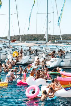 many people are swimming in the water near boats