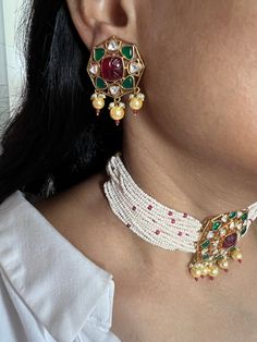 Adorn yourself with this gorgeous Indian Kundan Jewelry piece. You will definitely fall in love with the multicolored Kundan stone brooch at the center and the beautiful pearl strings on both sides.  Notice the pink beads weaved into the pearl strings.  Handmade by our skilled Indian craftsmen from Jaipur.  The statement Kundan studs add to the royalty of the wedding choker.  Material: Silver, Copper mix, gold plating, pearls, multicolored Kundan work. Dimensions Weight of choker is 46 g. Choker comes with adjustable Dori. Weight of Studs is 16 g per pair. Drop Length of Studs: 4 cms, push back closure. Width of Studs: 3 cms Preferred by celebrities and Indian film heroines for the royal Indian weddings. Multicolor Jeweled Earrings For Wedding, White Jeweled Bridal Necklace For Wedding, Multicolor Jeweled Bridal Necklace For Wedding, White Jeweled Bridal Necklace For Celebration, Jeweled White Bridal Necklace For Celebration, Traditional White Jewelry With Stones, Multicolor Gemstone Bridal Necklace For Wedding, Traditional White Stone Jewelry, Festive White Bridal Necklace With Gemstone