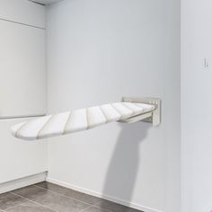 an empty white room with a long curved shelf on the wall and tile flooring