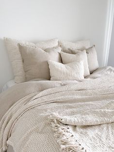 an unmade bed with white linens and pillows