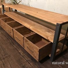 a wooden bench with drawers underneath it on the floor next to a bike rack and wall