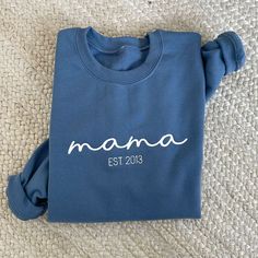 *Sample shown with White thread on Indigo sweatshirt* This cozy and stylish crewneck is the perfect custom gift for any mom. Whether you're a new mom looking to celebrate your little one's arrival or an experienced mama proud of your motherhood journey, this sweatshirt is a beautiful way to showcase your mama status. Crafted with love and care, this sweatshirt features custom embroidery of your Mama EST date. The embroidered date adds a personal touch that celebrates the special milestone in you Custom Text Long Sleeve Sweatshirt As A Gift, Casual Sweatshirt With Letter Embroidery As Gift, Blue Letter Embroidery Sweater For Fall, Blue Sweater With Letter Embroidery For Fall, Blue Fall Sweater With Letter Embroidery, Mother's Day Crew Neck Top With Embroidered Text, Mother's Day Embroidered Text Crew Neck Top, Customizable Casual Sweatshirt For Gift, Customizable Casual Sweatshirt For Gifts