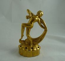 a gold colored figurine is sitting on a white surface and has its arms spread out