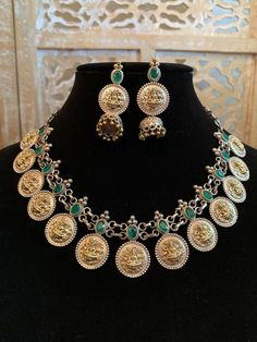 A really gorgeous jewelry set made from a mixture of pure brass (80%) and pure silver (20%). The design features small coin pine structures with Goddess Laxmi engraved on it neatly with a bright green stone on top of each coin. The earring is also same with a small jhumka added. The quality of the jewelry is top quality due to the use of authentic brass and silver. 100% guarantee on the gold and silver polish. Necklace is adjustable- loops in the back. Care Instruction: Avoid heat & substanc Temple Jewelry Sets With Matching Earrings, Ceremonial Brass Jewelry With Coin Pendant, Dual-tone Sterling Silver Round Jewelry, Silver Dual-tone Temple Jewelry Sets, Silver Dual-tone Metal Jewelry, Gold And Silver Dual-tone Necklace, Traditional Brass Coin Necklace For Gift, Traditional Brass Coin Necklace, Dual-tone Temple Jewelry In Brass