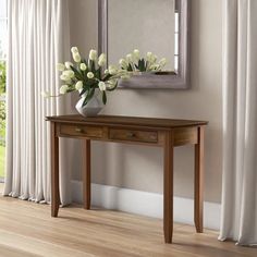 a vase with white flowers sitting on top of a wooden table next to a mirror