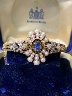 "This magnificent bracelet bangle dates back to the Victorian era. It is crafted in 14K gold. Centered with a natural vivid blue sapphire, and accented with antique natural pearls, and diamonds. Bracelet Circumference: 6.5\" Approximate Carat Weight of Sapphire: 0.60 Carats Approximate Carat weight of Diamond: 0.85 carats Smallest Measurement of Pearl: 1.5 mm x 1.5 mm Largest Measurement of Pearl: 4.0 mm x 4.0 mm Weight: 23.7 grams Metal Purity: 14KT Gold" Antique Diamond Round Bracelets, Antique Round Diamond Bracelets, Antique Blue Diamond Jewelry, Antique 17 Jewels Bracelet For Anniversary, Elegant Sapphire Diamond Bracelet For Wedding, Elegant Blue Diamond Bangle, Elegant Sapphire Bracelets For Wedding, Elegant Sapphire Wedding Bracelets, Vintage Diamond Bangle Jewelry