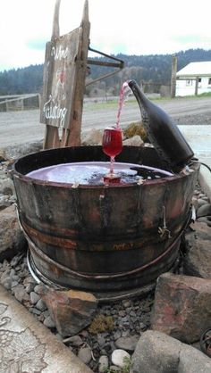 an old barrel filled with red liquid on top of rocks