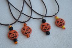 three necklaces with carved pumpkin faces on them