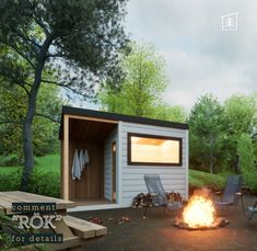 a small shed sitting next to a fire in the middle of a forest with chairs around it