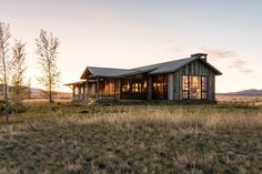 a small house sitting on top of a lush green field next to a dry grass covered field