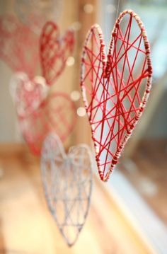 two heart shaped ornaments hanging from strings on a window sill in front of a mirror