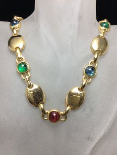 "Gorgeous David Grau necklace all done on brilliant gold plated metal. This necklace consists of eight flawed emerald, sapphire blue and ruby red round Cabochons with large oval brilliant gold discs between each one. Measuring 18\" by 5/8\". ABSOLUTELY GORGEOUS!" Gold Oval Multi-stone Jewelry, Vintage Gold Multi-stone Necklace, Yellow Gold Jeweled Necklace, Gold Multi-stone Oval Cabochon Jewelry, Gold Oval Cabochon Multi-stone Jewelry, Gold Oval Multi-stone Necklace, Gold Multi-stone Costume Jewelry, Oval Jeweled Gold Jewelry, Oval Multicolor Jeweled Jewelry