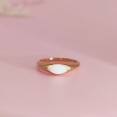 a gold ring with an oval shaped white stone