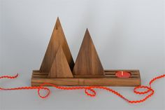 a wooden object with two mountains on it and a red string hanging from the end