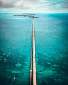 an aerial view of a long bridge in the middle of the ocean with blue water