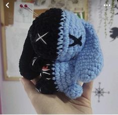 a crocheted black and blue stuffed animal is held up in front of the camera