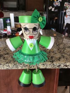 a green and white doll sitting on top of a counter