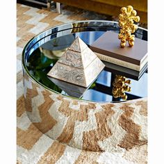 a glass table topped with books and a pyramid shaped object sitting on top of it