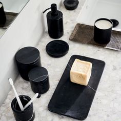 a soap bar sitting on top of a black tray next to cups and spoons