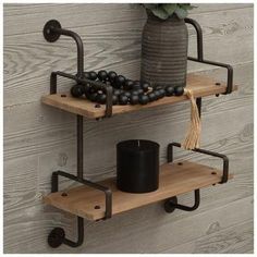 two wooden shelves with black balls on them and one shelf holding a candle, next to a potted plant