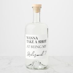 a bottle of vodka sitting on top of a white marble counter with a label reading, wanna take a shot at being my