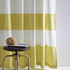 a stool with a book on top of it in front of a striped shower curtain