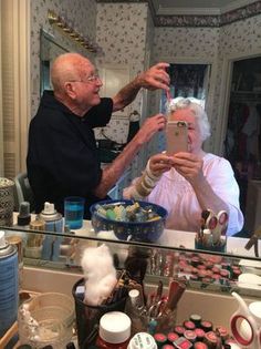 an older man taking a selfie in front of a bathroom mirror with his reflection