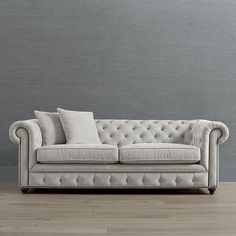 a couch sitting on top of a hard wood floor next to a gray painted wall