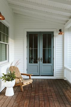 a wooden chair sitting on top of a porch next to a blue door and window