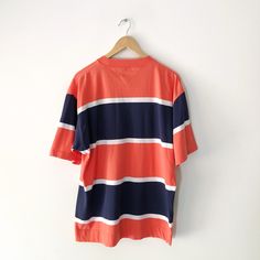 Vintage Tommy Hilfiger navy and orange striped t-shirt with embroidered logo on the pocket. 100% cotton. Size L Measurements: Length: 29 inches Pit to pit: 23 inches In good vintage condition. Navy And Orange, 90s Tees, Cap Sleeves Blouse, Black Graphic Tees, Vintage Tommy Hilfiger, Striped T Shirt, Blue And Orange, Logo T Shirt, Fancy Dresses