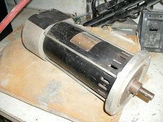 an old motor sitting on top of a wooden table next to some wires and other tools