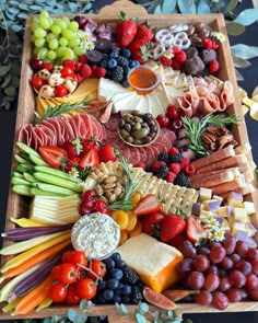 a wooden platter filled with lots of different types of cheeses and meats