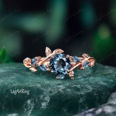 a gold ring with blue topazte surrounded by leaves on a green marble slab