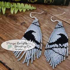 the earrings are made out of beads and have black and white designs on them, along with a green book