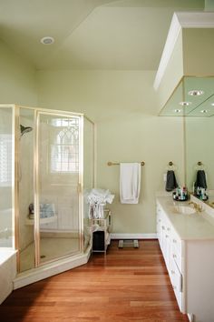 a large bathroom with wood flooring and white walls, along with a walk in shower