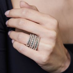 a woman's hand with three rings on her fingers and one ring in the middle