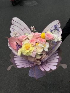 a bouquet of flowers in the shape of a butterfly is being held by someone's hand